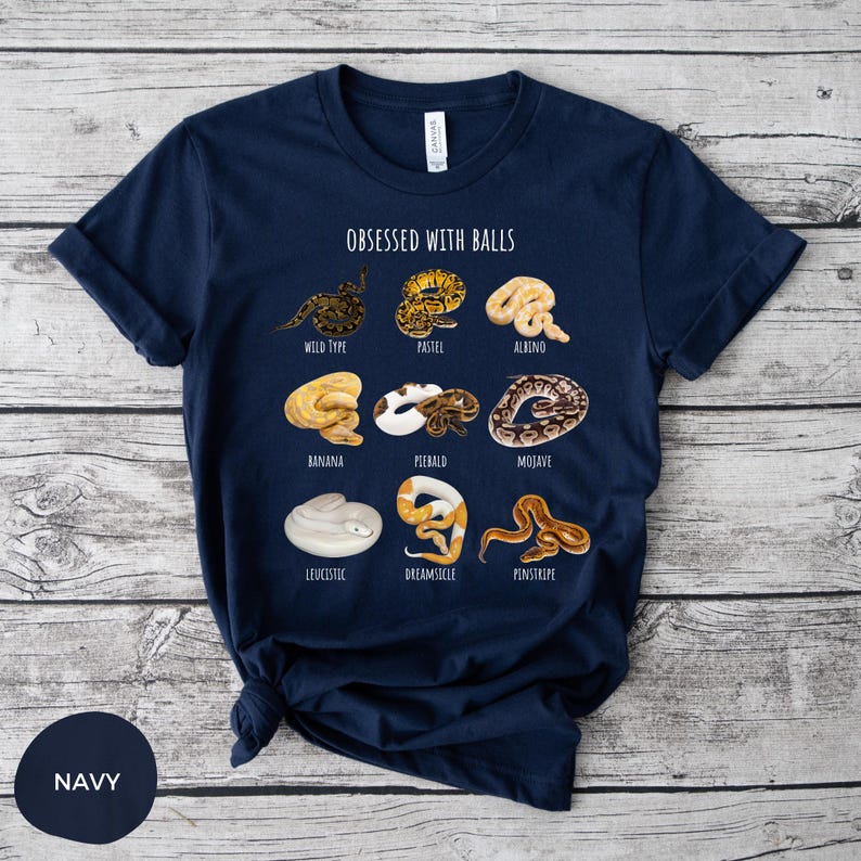 May include: Navy blue t-shirt with the text "OBSESSED WITH BALLS" and illustrations of various snake morphs. The shirt features a crew neck and short sleeves. The color of the shirt is navy.
