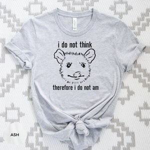 May include: A grey t-shirt with a black and white illustration of an opossum and the text "i do not think therefore i do not am".