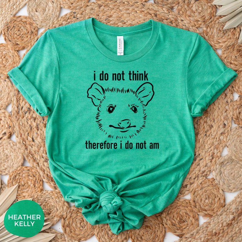 May include: A green t-shirt featuring a black and white illustration of an opossum and the text "i do not think therefore i do not am"