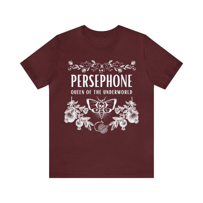 May include: A maroon t-shirt with a white graphic design featuring the text "PERSEPHONE QUEEN OF THE UNDERWORLD" with a moth and pomegranate imagery.
