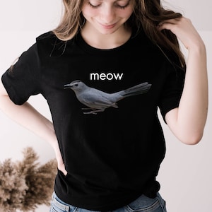 May include: Black t-shirt with a gray bird graphic and the word "meow" printed in white.