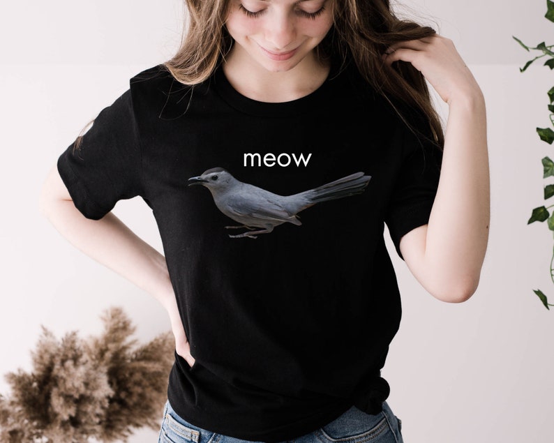 May include: Black t-shirt with a gray bird graphic and the word "meow" printed in white.