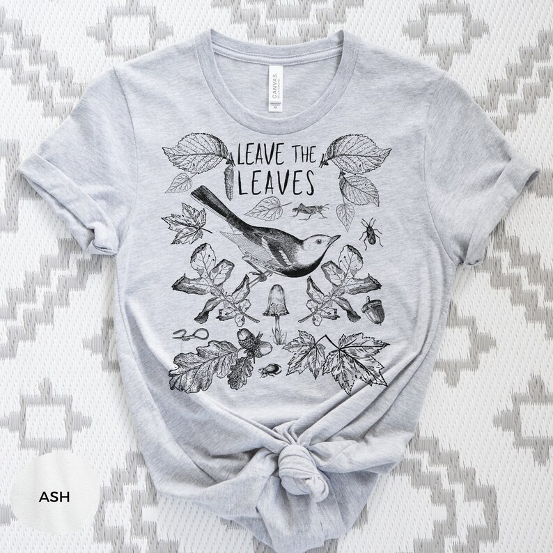 May include: A gray t-shirt with a black and white illustration of leaves, a bird, and insects. The text "Leave the Leaves" is printed on the shirt.