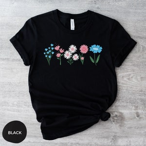 May include: Black t-shirt with a row of colorful flowers printed on the front. The flowers are pink, blue, and white.