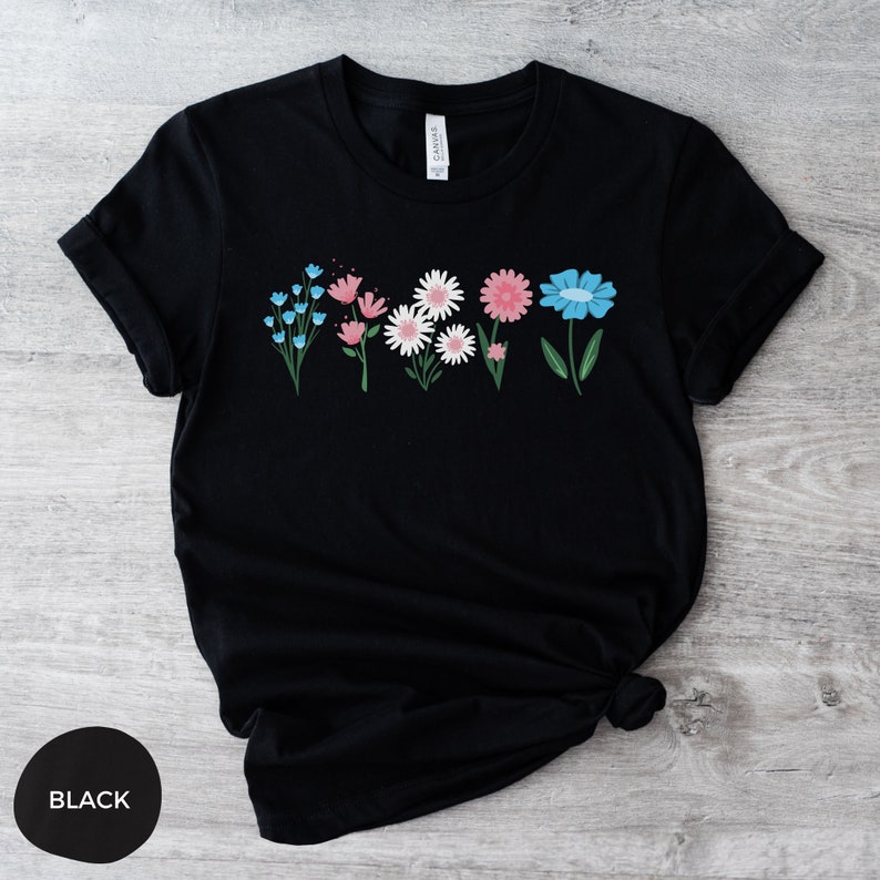 May include: Black t-shirt with a row of colorful flowers printed on the front. The flowers are pink, blue, and white.
