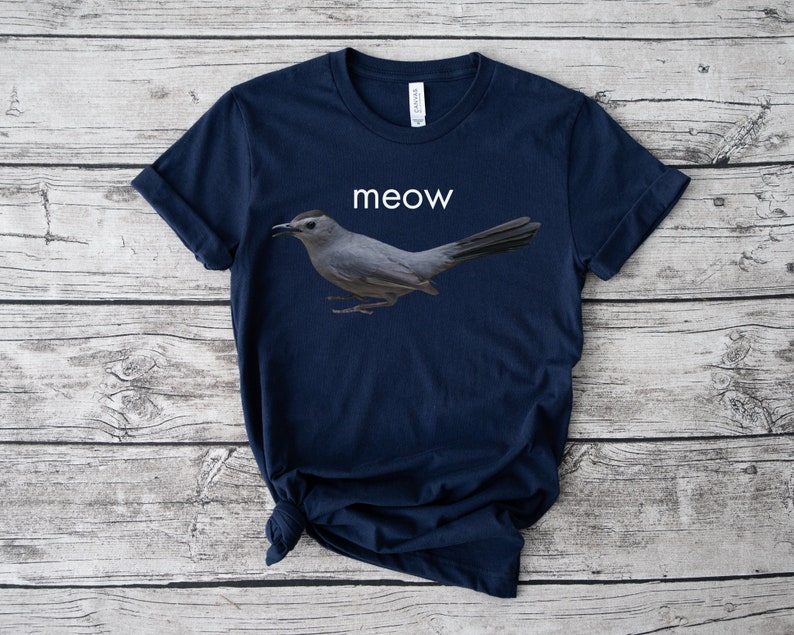 May include: A navy blue t-shirt with a gray bird graphic and the word "meow" printed in white.