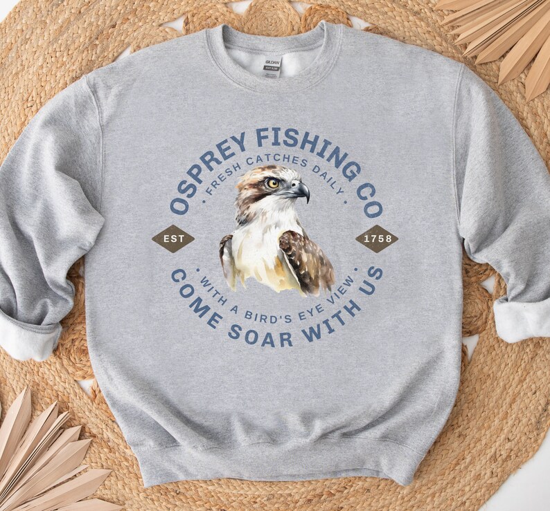 May include: Gray sweatshirt with a blue and white logo that says "Osprey Fishing Co. Fresh Catches Daily. Est 1758. Come Soar With Us. With a Bird's Eye View."