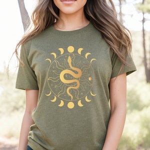 May include: A green t-shirt with a gold snake and moon design. The snake is coiled around a sun with rays. The moon phases are around the sun and snake.