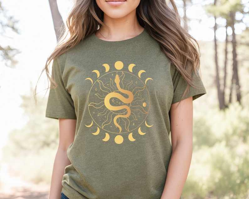 May include: A green t-shirt with a gold snake and moon design. The snake is coiled around a sun with rays. The moon phases are around the sun and snake.