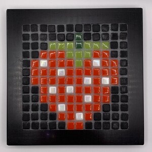 Peut inclure: Une œuvre d'art en mosaïque représentant une fraise rouge avec une tige verte, sur fond noir. La fraise comprend des carreaux blancs pour les reflets, encadrée par un carré noir.