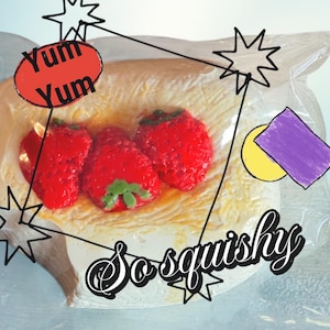 May include: A clear plastic bag containing three bright red strawberries with green stems, resting on a light-colored pastry. The image includes the text "Yum Yum" in a red oval and "So squishy" in a cursive font.