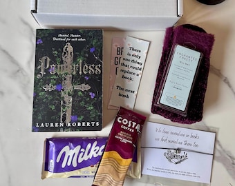 May include: A gift box with a book titled "Powerless" by Lauren Roberts, a Milka chocolate bar, Costa Coffee, bookmarks, purple socks, and a bracelet. The book cover has a silver cross design. The box also contains a wax melt.