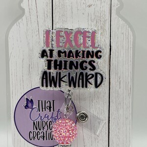 Peut inclure: Un porte-badge en acrylique transparent avec le texte "I EXCEL AT MAKING THINGS AWKWARD" en lettres pailletées roses et noires. Le porte-badge présente un charme perlé rose et noir et un cercle violet avec le texte "THAT Crafty NURSE CREATIONS".