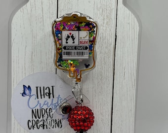 May include: A clear badge reel with a "Pixie Dust" design, featuring a Mickey Mouse silhouette and the word "Believe". The reel has a red beaded accent and a black and white polka dot bead.