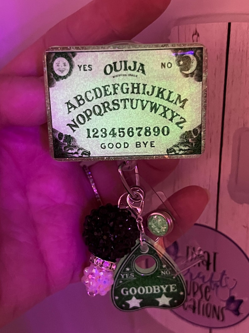 Puede incluir: Un portatarjetas con un dise&ntilde;o de tablero Ouija en miniatura, que incluye el alfabeto, n&uacute;meros y las palabras "YES", "NO" y "GOOD BYE". Incluye un dije de cuentas negras, un dije de planchette y un acento de purpurina verde.