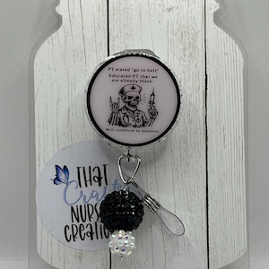May include: A retractable badge reel with a black and white design. The reel features a circular image with a skeleton in a nurse's uniform holding a syringe. Text on the image reads "PT stated 'go to hell.' Educated PT that we are already there."