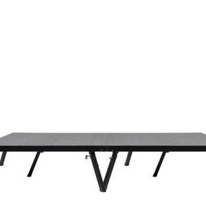 Op de afbeelding: Een zwarte opklaptafel met een houten blad en vier poten. De tafel is ingeklapt en klaar om te worden vervoerd.