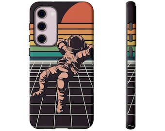 May include: A phone case with a retro design. It features an astronaut reclining on a grid, set against a sunset in orange, yellow, and green. The case is black, with a side view showing coloured buttons.