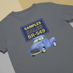 May include: A gray t-shirt with a blue pickup truck and a yellow sign that says "SAMPLES SALES BR-549".