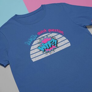 May include: Blue t-shirt with the text "hey, quick question, WTF?!" in a retro comic book style. The design features a pink burst, blue and white text, and a white and gray striped background. The shirt is a solid blue color.