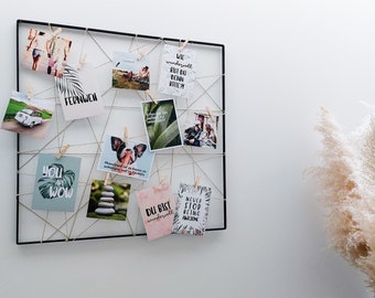 May include: A black metal grid with string and wooden clothespins holding various postcards with inspirational quotes and images. The quotes include "You are wow", "Du bist wundervoll", "Never stop being awesome", and "Wie wundervoll bist du denn bitte?"