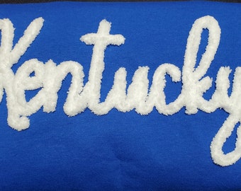 May include: A royal blue sweatshirt with the word "Kentucky" in white fluffy lettering.