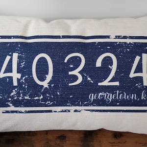 May include: A white pillow with a blue rectangle featuring the number 40324 and the text "georgetown, ky" in white.