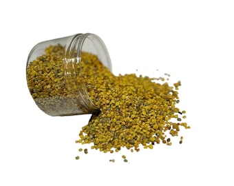 May include: A clear glass jar with a yellow and green bee pollen spilling out onto a white background.