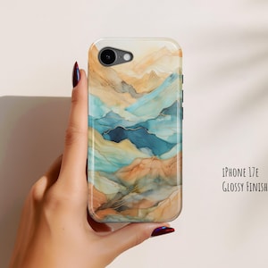 May include: A phone case for an iPhone 17E with a glossy finish, featuring an abstract landscape design in shades of blue, tan, and cream. The pattern resembles layered mountains or fluid ink washes with subtle gold-toned veining throughout.
