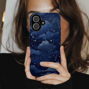 May include: A navy blue phone case with a matte finish, featuring a celestial design of white clouds, stars, and a dark blue night sky. The case has a camera cutout and the words "MATTE FINISH" are printed at the bottom.