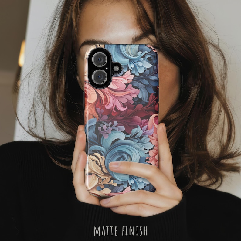 Puede incluir: Una funda para smartphone con acabado mate que presenta un denso patr&oacute;n floral con remolinos en tonos rosa empolvado, burdeos intenso, azul apagado y crema. El dise&ntilde;o cubre toda la superficie posterior, incluyendo el &aacute;rea de la c&aacute;mara dual.