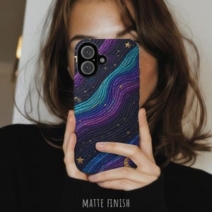 May include: A smartphone case with a matte finish featuring a textured, wavy pattern in shades of deep purple, dark blue, and teal. The design is accented with small gold stars and a crescent moon, creating a celestial aesthetic on the back cover.