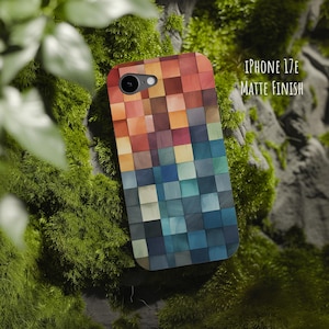 Op de afbeelding: Een telefoonhoesje voor een iPhone 17e met een matte afwerking, voorzien van een rasterpatroon van kleine vierkantjes in een kleurverloop van warme oranje en rode tinten aan de bovenkant naar koele blauwe en donkergrijze tinten onderaan.