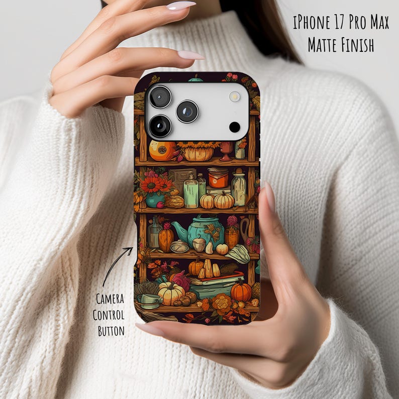 May include: An iPhone 17 Pro Max matte finish case featuring a detailed illustration of a shelf filled with pumpkins, flowers, and various decorative items. The case has a dark background and the text "CAMERA CONTROL BUTTON".