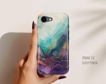 Puede incluir: Una funda para iPhone 17E con acabado brillante, que presenta un diseño de acuarela abstracto en tonos verde azulado, azul y morado con finas vetas doradas. La funda tiene un recorte circular para el objetivo de la cámara.