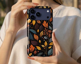 May include: A smartphone case featuring a repeating pattern of autumn leaves in shades of orange, yellow, brown, and muted blue against a black background. The case has a dark blue camera module cutout with three circular lenses and a flash.
