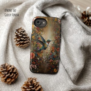May include: A glossy iPhone 16E case featuring a vibrant hummingbird design amidst colorful flowers. The case has a black border and a glossy finish. The text "IPHONE 16E GLOSSY FINISH" is printed on the case.