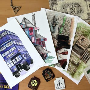 May include: A collection of watercolor art prints featuring scenes from a fantasy series. Includes a purple double-decker bus labeled "Knight Bus", a house, a wolf, and a building. Also includes a "London to Hogwarts" ticket and themed accessories.