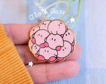 Puede incluir: Un pin de color dorado con un grupo de personajes rosados de Kirby, todos acurrucados. El pin dice "Kirby Ball" en texto blanco.