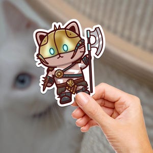 May include: A sticker of a cartoon cat wearing armor and holding an axe. The cat has a golden helmet with glowing blue eyes and is wearing a brown leather strap across its chest. The axe is silver with a brown handle.