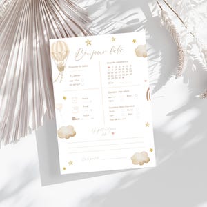 Peut inclure: Une carte d'annonce de naissance avec le texte "Bonjour bébé" et une illustration de montgolfière. La carte comprend des sections pour le nom du bébé, le sexe, la date de naissance et d'autres détails. Éléments décoratifs : étoiles et nuages.