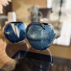 Peut inclure: Deux vases en céramique bleus avec une finition émaillée. Un vase a un motif en spirale blanche, tandis que l'autre a un motif de serpent en relief.