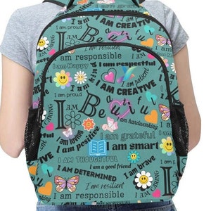 Puede incluir: Una mochila azul verdosa con una cremallera negra y un bolsillo de malla. La mochila está cubierta con un patrón colorido de mariposas, flores y las palabras "Yo soy" seguidas de afirmaciones positivas como "creativo", "responsable" y "considerado".