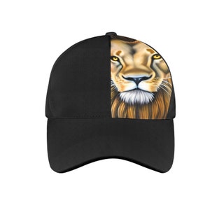 May include: Black baseball cap with a lion's face printed on the side. The lion's face is in focus, with its eyes, nose, and mouth clearly visible. The lion's mane is a mix of brown and gold.