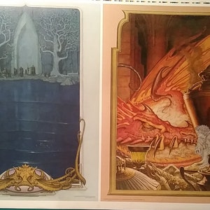May include: Two framed fantasy art prints. The left print shows a blue and white scene with two trees and a group of figures standing in front of a large archway. The right print shows a red dragon with a gold and orange background. A small figure is standing near the dragon.