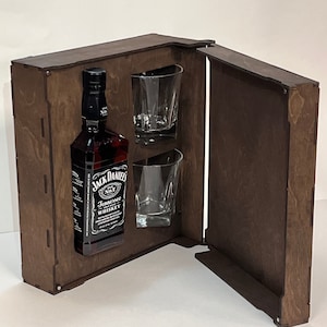 May include: A wooden box with a hinged lid, containing a bottle of Jack Daniel's Tennessee Whiskey and two clear glass shot glasses.