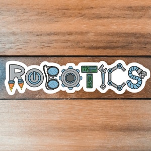 May include: A sticker with the word "ROBOTICS" in a playful, illustrated style. The letters are designed with robot-themed elements like rockets, gears, and circuit boards, in shades of gray, blue, and green. The sticker is on a wooden surface.