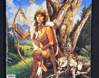 Può includere: La copertina della rivista Dragon, numero 94, presenta una donna con lunghi capelli castani che indossa un abito di pelle marrone e tiene un arco e una freccia. È seduta su uno scoglio con un piccolo animale al suo fianco. La copertina della rivista include anche il testo "Dragon" e "$3.00".