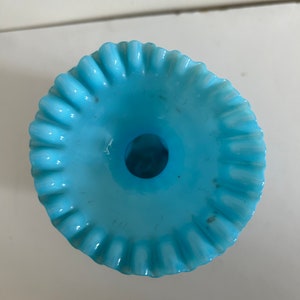 May include: A light blue glass vase with a ruffled rim. The vase has a wide opening and a narrow base.