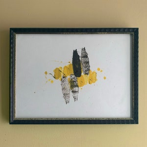 May include: A framed abstract painting with black and yellow paint splatters on a white background.